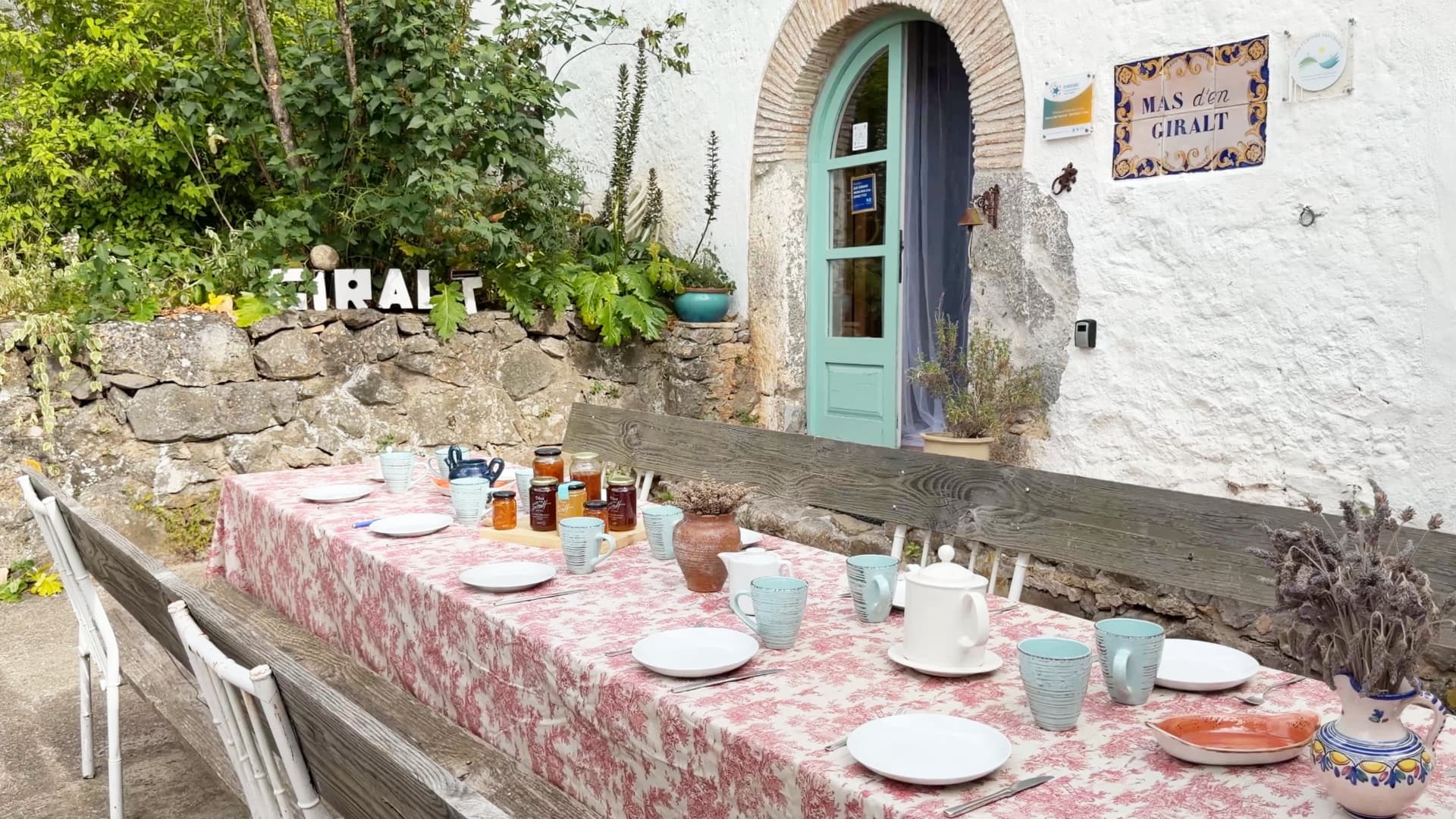 Mesa de desayuno vestida junto a la puerta azul de la masía